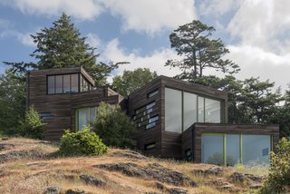 Bonnie and Paul Bunning’s 3,600-square-foot home is composed of four stacked volumes covered in cedar and cypress. The door and window frames are painted Tasty Apple, Perennial, and Herb Garden by Benjamin Moore.