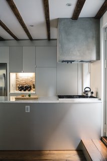 The kitchen range hood is framed in wood, wrapped with cement board, and parged with a thin layer of polished concrete. The sides of the Carrara-topped island are clad in anodized aluminum, as are the IKEA cabinets. 