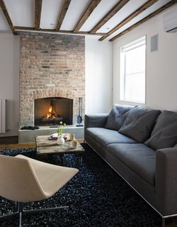 A WH Design sofa and an Arper Catifa 80 chair rest on a Nanimarquina rug made <br>of recycled bike tires. 
