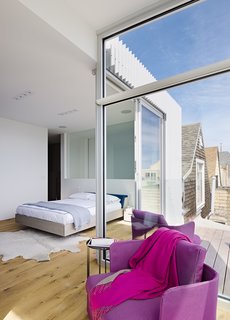 After a Renovation, a Classic San Francisco Victorian Is Now Bursting With Light and Color - Photo 9 of 15 - Set on the home’s top floor and featuring a deck that overlooks the backyard, the master bedroom is clean-lined and filled with light.. The Fusion bed is by Zeitraum; the purple Cove chairs are by Paola Lenti.