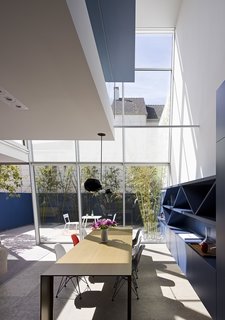 After a Renovation, a Classic San Francisco Victorian Is Now Bursting With Light and Color - Photo 11 of 15 - Transforming the rear of the house is something more often found in a high-rise building—a curtain wall that Fougeron and the team hung from the third floor. "It’s actually very complicated to make the field glazing look simple and minimal," says the architect. Piero Lissoni’s Metallico table for Porro anchors the dining area, while built-in cabinetry offers ample storage. The main living area was created from what was once a basement behind the garage. Limestone floors inside and out unify the living spaces.