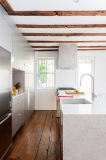 The 12-foot kitchen island, topped in polished Carrara marble, has a waterfall edge and an integrated apron sink made from the same stone slab.