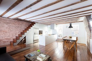 Custom finishes in anodized aluminum meet original exposed ceiling beams and brick walls in the kitchen.