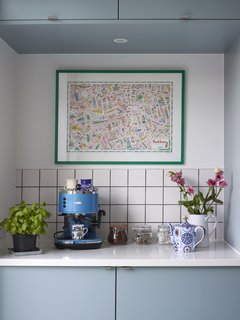 A cerulean espresso machine by Gaggia anchors a kitchen counter tableau. The cabinetry doors are Lastra in Fjord blue by Crown.