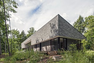Vince and Adrienne Murphy’s rural retreat is clad in gray shingles and gray-stained pine. "They wanted the cottage to meld into the woods and be visually quiet," says architect Kelly Doran, who worked with Portico Timber Frames to build the 2,500-square-foot home.