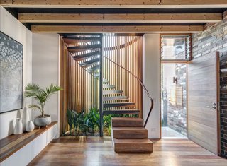 A Sustainable Home Near Sydney Boasts Chicken Coops, Vertical Gardens, and More - Photo 4 of 9 - A cylindrical glass staircase with Western red cedar and painted steel mullions dominates the front of the house. The stair treads, along with the floor, are made of recycled spotted gum.