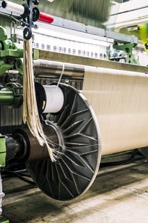 <b>5 Tie the Warp </b> Once the yarns have been wound onto the drum of the warping machine, they get transferred—literally unwound—onto a warp beam. The warp beam is then put into the back of a loom and prepared for weaving.