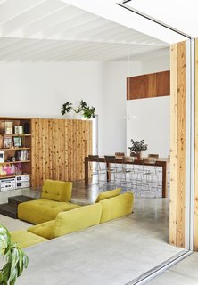 This DIY Home in New Zealand Doubles as a Coffee Spot and Art Gallery - Photo 6 of 16 - In the living area, a cedar storage unit made by Grant features a five-by-five-foot sliding panel that conceals shelving and the television. "It’s a way to make it feel less like a TV room during the day," Beer says. The sunken sofa—a throwback to the residents’ childhoods in the 1970s— is from the Houdini collection by King Living. The dining chairs were a secondhand purchase.