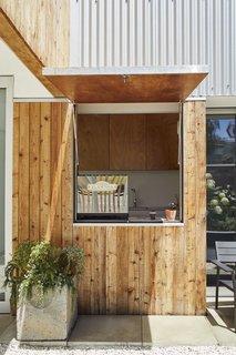 This DIY Home in New Zealand Doubles as a Coffee Spot and Art Gallery - Photo 12 of 16 - <b>Coffee Kiosk:</b> Accessible through a sliding millwork wall, the coffee kiosk doubles as a laundry room (the washer and dryer are hidden behind cabinets). A hatch window opens the space, which is outfitted with a refurbished 1997 Elektra espresso maker.