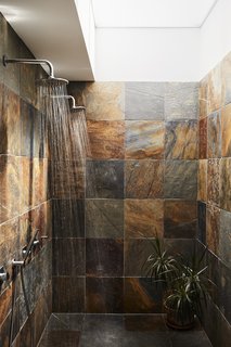 This DIY Home in New Zealand Doubles as a Coffee Spot and Art Gallery - Photo 9 of 16 - Covered in slate squares from Cambridge Tile, the master bathroom includes a double shower <br>with rain heads by M&Z Rubinetterie. A skylight lets in natural light while maintaining the residents’ privacy.
