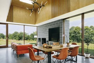 Two Designers Create a Small but Luxe Retreat in the Catskills - Photo 3 of 8 - Polished concrete blocks and a concrete floor are contrasted by a birch plywood tray ceiling. Paola and Jason cut the vertical strips in the ceiling themselves and placed fabric behind to soften the acoustics. Custom brackets were added to the modular seating from West Elm, the table top and legs were found on Etsy, and the chandelier is by Avenue Lighting. 