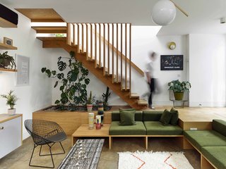 A planter is integrated under the open staircase leading to the upper floor, and a skylight in the roof illuminates the stairwell. 