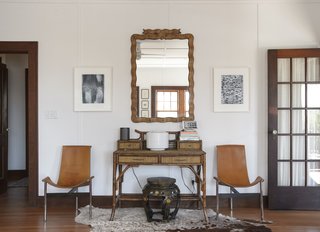 Owner Michael Silber introduced an eclectic mix of furniture with help from interior designer Tracey Garet. By the front door, an antique mirror hangs over a rattan desk; the leather T chairs are by Katavolos, Littell & Kelley.