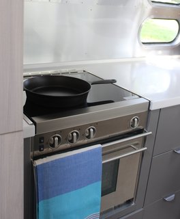 The well-appointed kitchen features Corian surfaces, a Baraldi hood vent, and a glass cooktop. A slide-out pantry and a slide-out convection microwave make prepping meals a cinch.