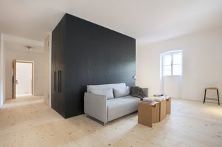 The second-floor vacation suite has a convertible Softline sofa and cardboard stools from Strange Design. The storage unit is clad in black MDF. 