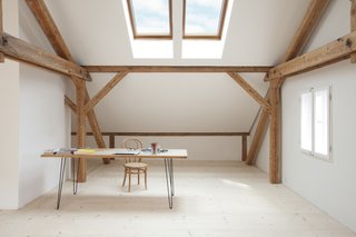 Sunlight streams into Reinhold and Verena’s loft through Velux skylights in the pitched roof. Reinhold fastened hairpin legs to an old table to create a desk, pairing it with a bentwood chair. The untreated spruce floorboards—many of which are a foot wide and 14 feet long—come from a stand of trees on the property and were milled on-site. The walls are coated in a custom lime-based paint. 