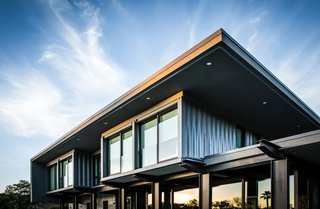 On the other side of the entry gate, the containers’ raw corrugated shells are exposed and topped with a gravel-ballasted roof that juts past the envelope to limit solar gain. 