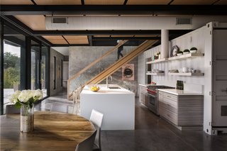 For the open-plan first floor, interior designer Sarah McFadden paired a round Mexican olive wood table by Taracea with Nuvola chairs covered in ash gray leather. A half-sized container, painted in Smoke Embers by Benjamin Moore, serves as a pantry/scullery. 