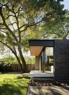 The master bedroom was raised and cantilevered so as not to disturb the mature oak tree roots. Boulders are used as steps to the lawn.