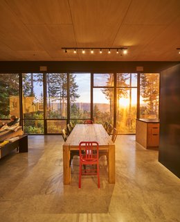 For ventilation, many of the valley-facing windows, measuring 10 ½ feet tall, feature a section at the top or bottom that opens. Navy 111 chairs, part of Emeco’s Coca-Cola edition, sit at the heads of a Restoration Hardware table; WAC track lights provide illumination. The floors are made of poured-in-place concrete.