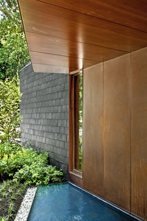 Bluestone slabs lead across a pair of reflecting ponds to the sapele mahogany front door.