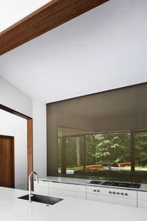 The owners have a wall of reverse-painted glass in the kitchen so they can gaze at the trees as they cook. The faucet is by Brizo.