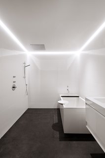 The guest bath, located in the lower level of the house, has a tub by Wetstyle. LED lights are recessed in a channel along the drywall ceiling. 