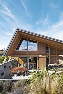 On a scenic but exposed lakefront site on New Zealand’s South Island, architects Tim Lovell and Ana O’Connell of Lo’CA created a pitch-roofed 2,690-square-foot residence for Tim’s parents. The home’s courtyard was excavated to help shelter it from high winds. A 10-foot eave over the windows and doors assists with sun shade and heat retention during the intense summer and winter months. 