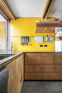 Many of the gaboon plywood cabinets are push-click. The accent wall is painted Fuel Yellow by Resene. 
