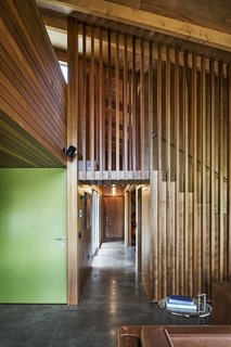 Bursts of color, like the front door painted in Kombi green by Resene are counterbalanced by pared-down concrete flooring and exposed bulbs. 