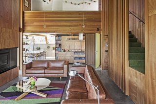In the living area, a Tolomeo lamp from Artemide sits near two Longreach sofas from Thonet. A slatted cedar balustrade stretches to the ceiling of the voluminous parlor.