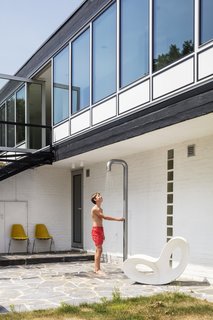 A Voido rocker by Ron Arad for Magis sits by the outdoor shower. 