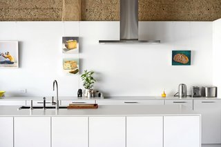 The kitchen features SieMatic cabinetry, Neolith countertops, and a faucet by Dornbracht. Mike Geno’s paintings of bread and cheese hang near a Lee Materazzi photograph.