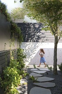 A black-stained Western red cedar fence now runs along the perimeter of Sharen McLean and Mark Derraugh’s property in Vancouver, part of a complete revamping of the couple’s outdoor space. The project was spearheaded by Sharen’s daughter, Andrea McLean, whose daughters and nephew make the most of the urban oasis. 