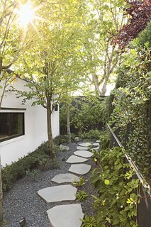 Katsura trees, climbing hydrangeas, and basalt stepping stones create a pleasing passageway between the lower back deck and the new garage. "What could have been leftover space, I wanted to be a promenade," says Andrea.
