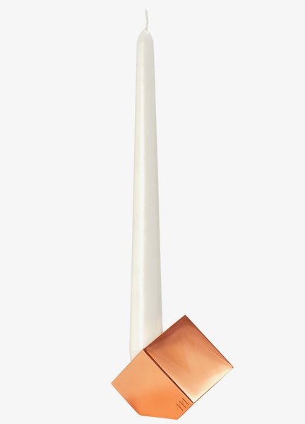 The copper cube-shaped Tilt candleholder by Sara Jaafar appears to balance on a corner.