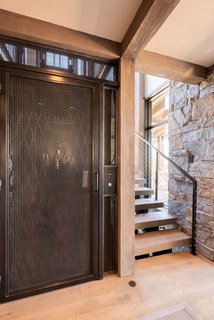 A steel elevator, wrapped by a staircase, anchors the home and descends downstairs to the bunk room. 
