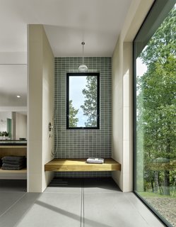 In the bathroom, blue-gray Heath Ceramic tiles and Linen Brix tiles by Naoto Fukasawa line the shower. 