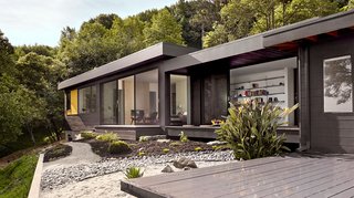 Chris and Laura Porter’s new master suite connects to the rest of the house via an indoor/outdoor bridge that comprises a covered deck and small library; Bonelli windows and Fleetwood sliders look out on a landscape designed by Christine Ferris. 