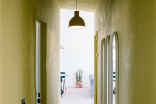 A chartreuse-colored corridor leads to the main living space. A Mutto pendant hangs above a series of Menu Oval Mirrors.