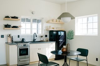 In the kitchen and dining area, the Akoya pendant by Rich Brilliant Willing hangs over a Bend Goods Bistro Table; the Hoist Sconce over the Signature Hardware kitchen sink and faucet is also by RBW. A Material Kitchen cookware set and Kinto coffee set outfits the kitchen, along with Neenineen ceramics and Snowe glassware. A SMEG fridge adds a retro touch.
