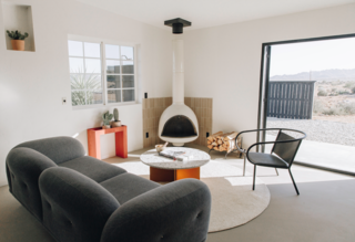 The living room provides a cozy gathering place anchored by a vintage fireplace from Urban Americana and Cle Tile backsplash. A circular Weave Rug pulls the space together.