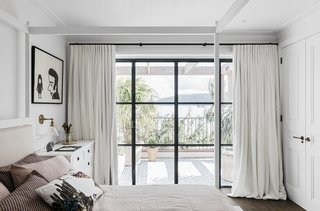 A guest bedroom offers floor-to-ceiling windows and a private balcony. 