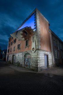 The unzipped building glows from within at night.