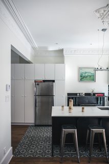 IKEA cabinets create storage around a Frigidaire refrigerator. The ornate molding maintains the historic character of the house.
