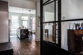 A custom glass-and-steel partition, made by Atelier Gris, separates the living room from the kitchen while maintaining visibility between the spaces.