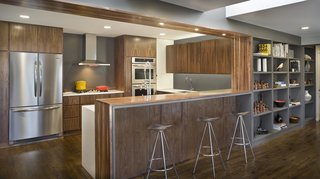 In a 1960s house in Overland Park, Kansas, Forward Design | Architecture remodeled a kitchen, family room, and mudroom. Walnut cabinets integrate the appliances to create a seamless look.