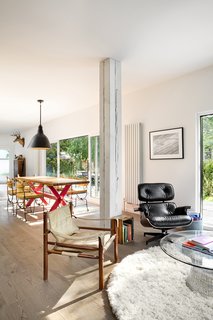 A playful approach to furnishings defines the interior. A mix of traditional items and modern pieces, among them an Eames chair and Warren Platner coffee table in the living area, fills the home. What looks like an exposed wood beam column in the open-plan living and dining space is in fact a pillar covered in wallpaper.