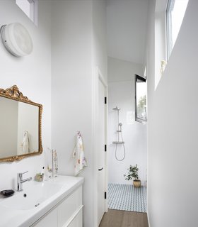 The en-suite master bathroom features an IKEA vanity and a curbless shower clad in Palau Celeste tile.