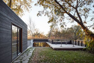 Nature Reigns Supreme at a Verdant Kansas City Home - Photo 2 of 9 - The roof, which extends into a deck, appears to float above the ground. A detached studio building is located on the site's upper level.